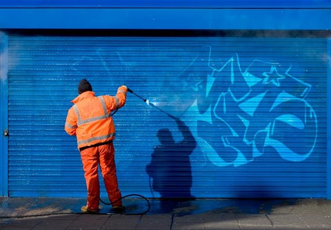 A work cleans graffiti from a garage door