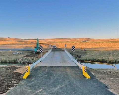 A photo of the new concrete single-lane Redcliffe Bridge shortly after completion, with rolling hills in the background in the late afternoon sun.