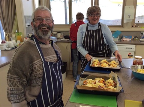 People smiling with prepared dishes ready to cook