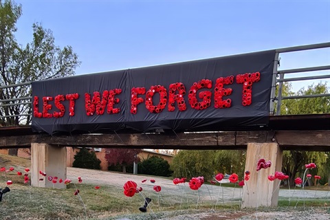 A floral arrangement spelling out 'Lest We Forget' on the footbridge in Berridale, 2021