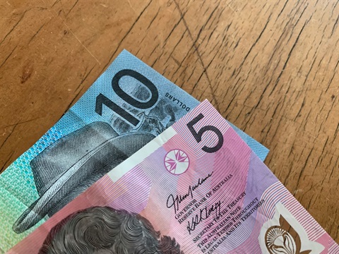 Close-up of corner of Australian $5 and $10 note on a table
