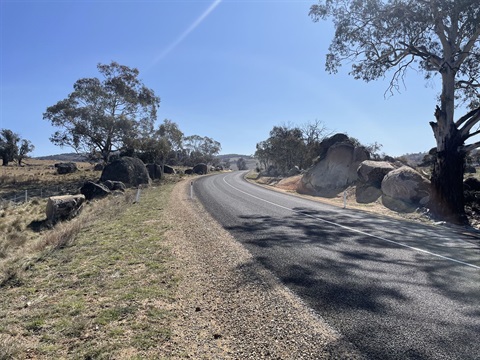 Upgraded section of Bobeyan Road, winding uphill with rocks, boulders, trees and rolling hills either side