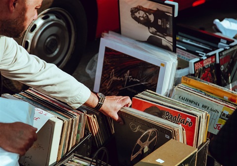 A person flipping through vinyl LP records at a garage sale