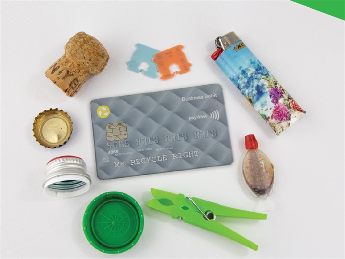 A collection of small items that must be kept out of recycling bins, including a peg, lighter, cap, lid, cork, and bread tag - with credit card for scale.