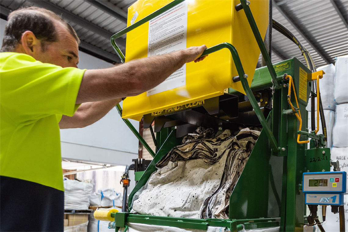A worker in a high vis vest processes waste material in an industrial facility