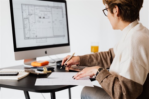 A woman looking at architectural plans on a desktop computer