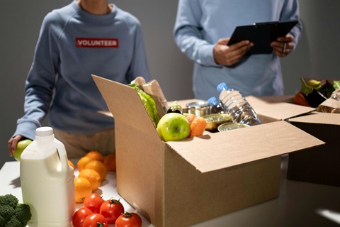 Volunteers in background behind trestle table of food and perishable donations