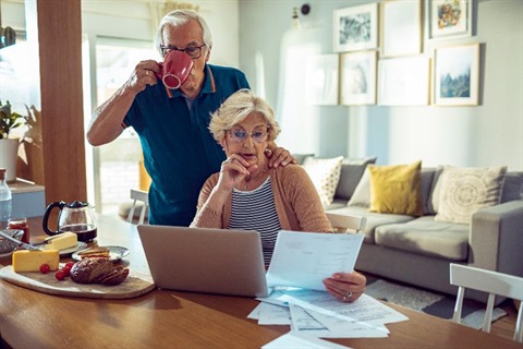 A couple sitting at a table in a house and looking at a bill